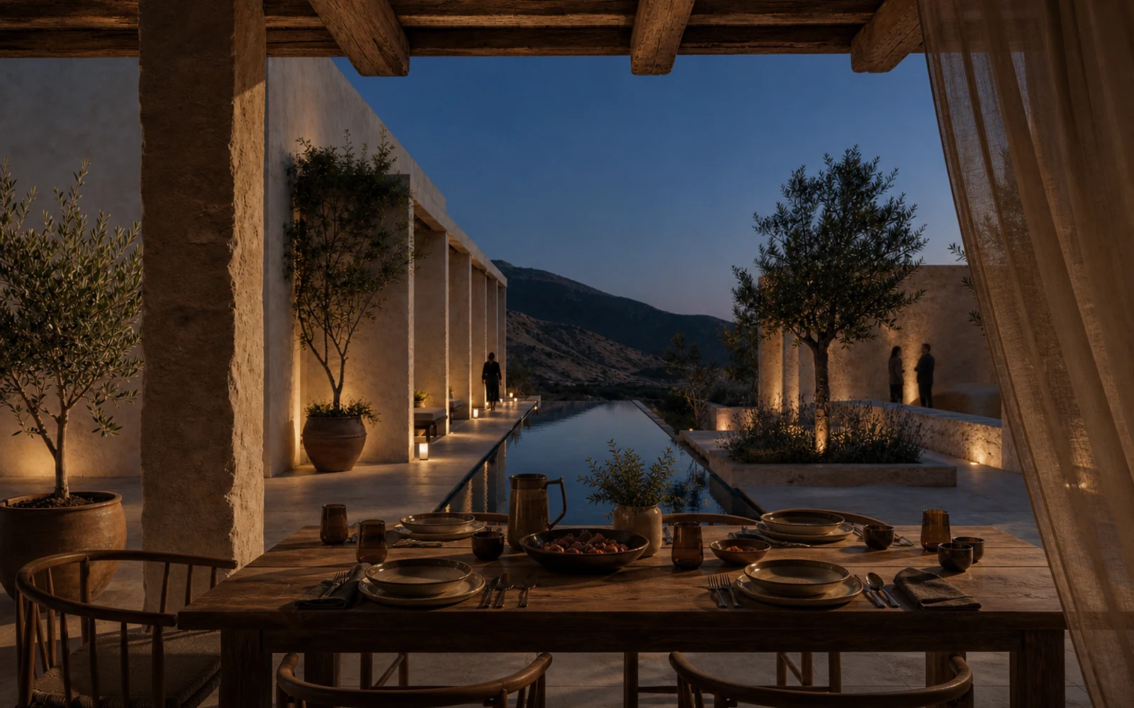 A long dining table beside the retreat's reflecting pool at blue hour with warm architectural light.